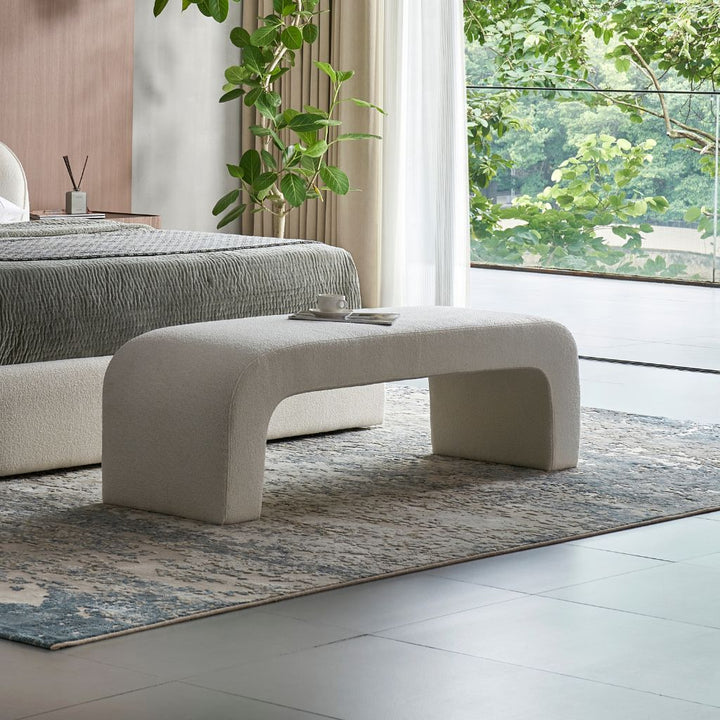 Pescara Ottoman with a curved upholstered design at the foot of a bed