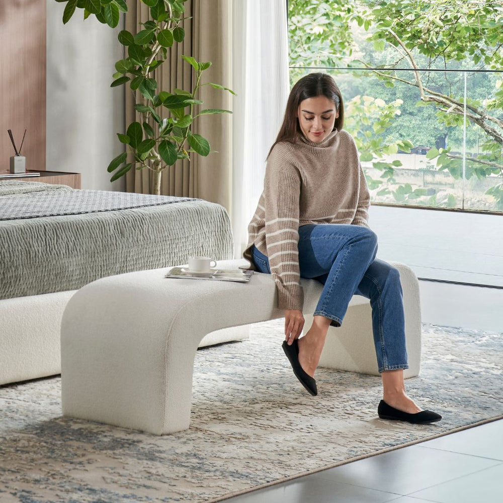 Pescara Ottoman in upholstered fabric showing the curved silhouette