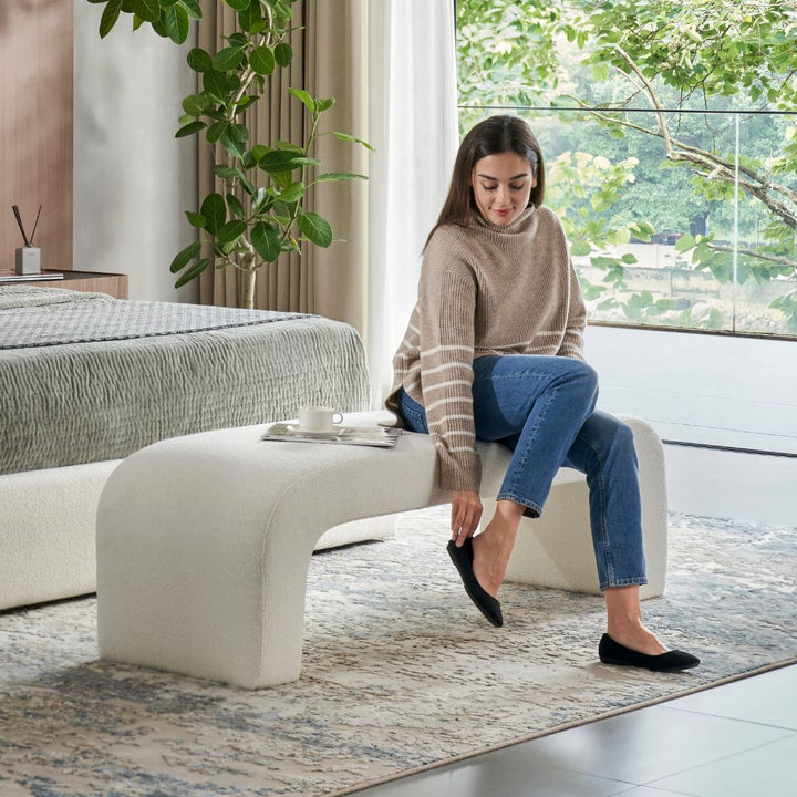 Pescara Ottoman in upholstered fabric showing the curved silhouette