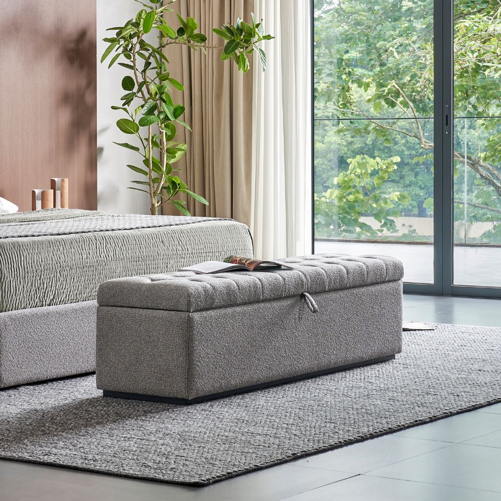 Vancouver Storage Ottoman with a tufted seat at the foot of a bed
