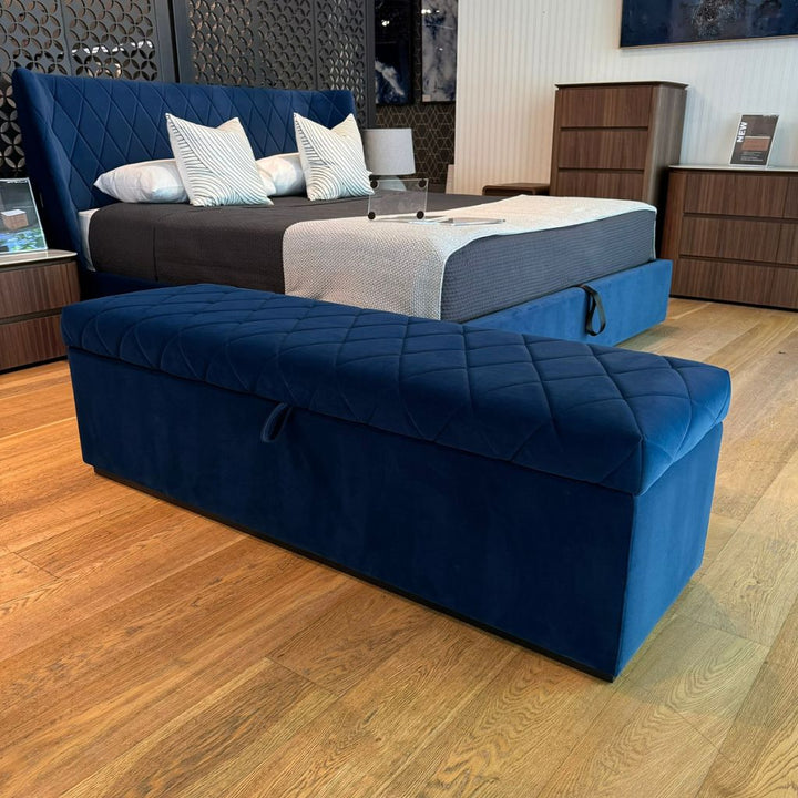 Verona Storage Ottoman with a patterned upholstered seat at the foot of a bed